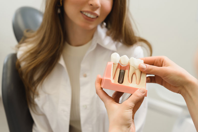 Dental Patient Getting Shown A Dental Implant Model During Her Consultation in Houston, TX